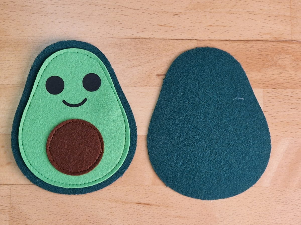 Die fertige Vorderseite mit Gesicht und Kern neben der zweiten, leeren dunkelgrünen Schale