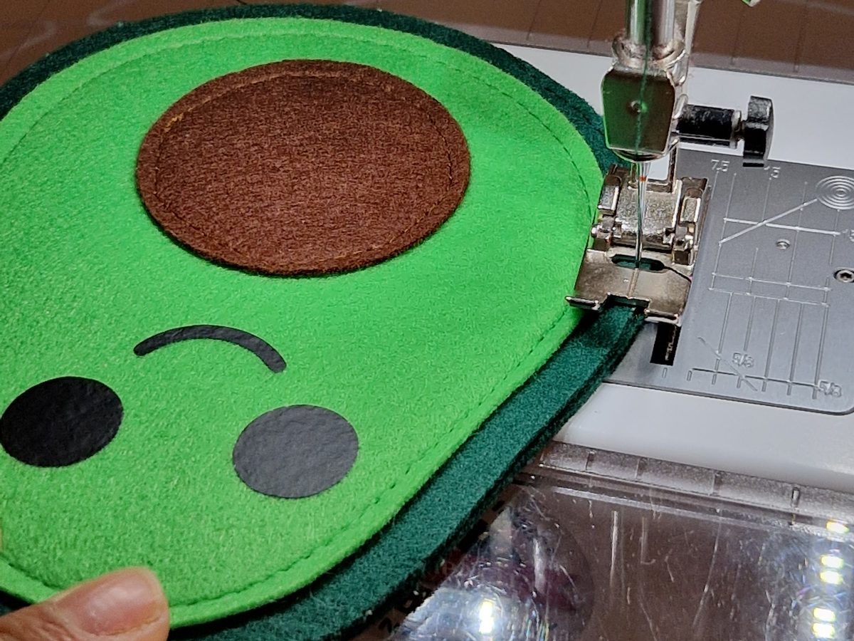 Die fertige Vorderseite mit Gesicht und Kern neben der zweiten, leeren dunkelgrünen Schale, weitere Ansicht 2