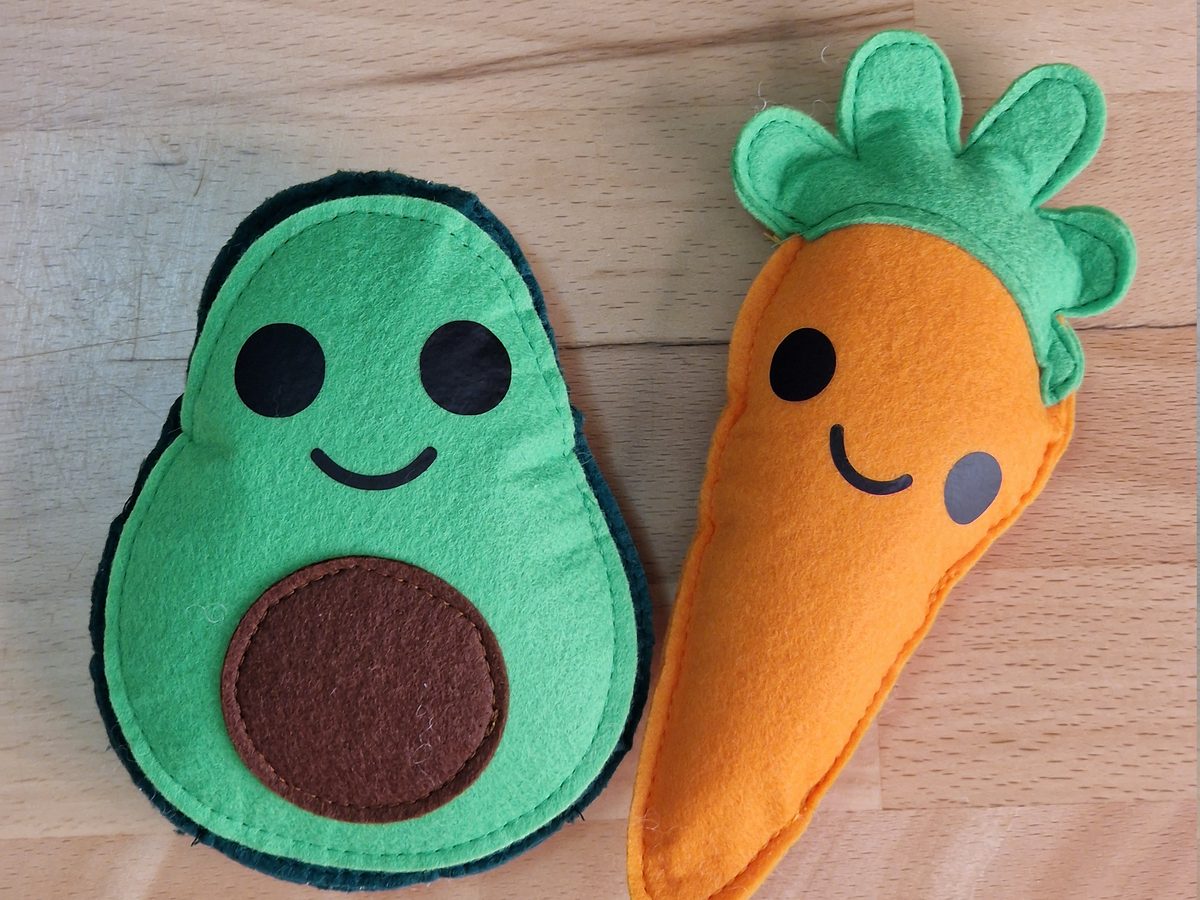 Die fertige Filzmöhre neben einer Avocado aus grünem Hartfilz mit braunem Kern, beide mit Gesicht